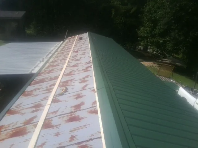 Old rusted panels beside newly installed green metal roofing — Wind Damage Roof Repair by Roofing Brothers in East Schodack