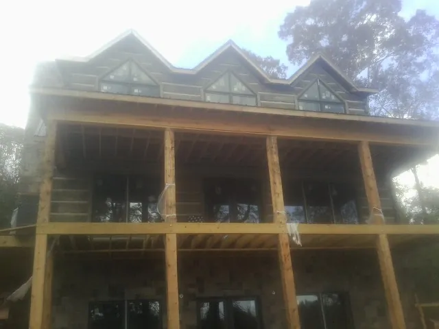 Dormers and porch framing on a large log home under construction — Roof Coating work by our crew in East Schodack