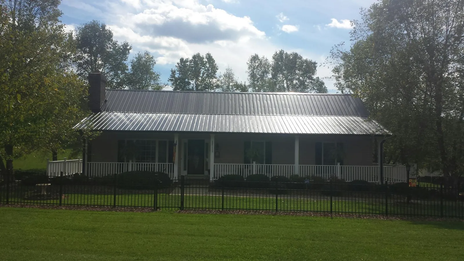 Gray metal roof on a brick ranch with a full width front porch — Gutter Guard Installation work by our crew in East Schodack