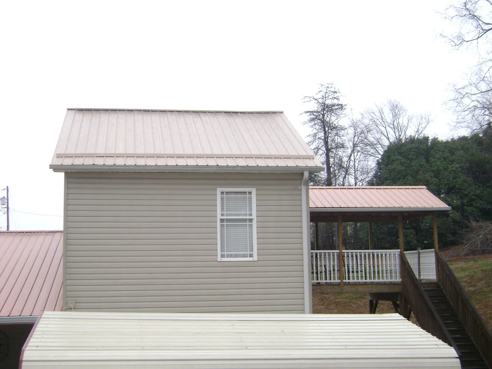 Tan metal roofs on a two story addition and attached porch, from a Roof Replacement job in East Schodack
