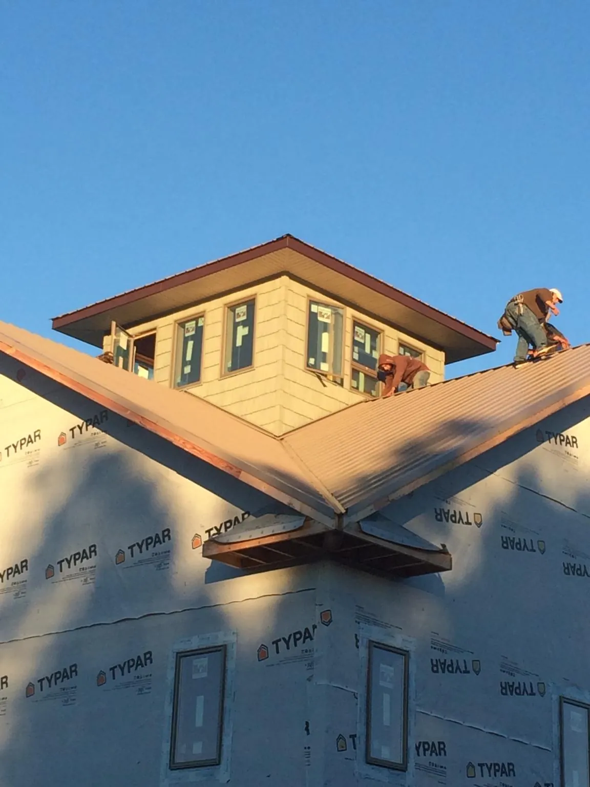 Roofers working around a rooftop cupola on a new metal roof at sunset — Roof Waterproofing in East Schodack by Roofing Brothers